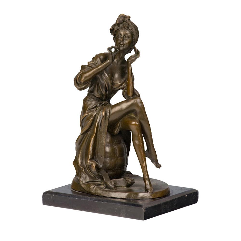 This is a bronze sculpture of a seated woman. She sits on a spherical object, wearing loose clothing with delicately and realistically depicted fabric fold textures; one hand gently holds a small item, while the other rests on her cheek, exuding a charming and elegant demeanor. There is a small decoration beside her feet, fully showing soft and agile charm. The overall craftsmanship is exquisite, vividly conveying the soft charm of the woman, and it has high decorative ornamental value.