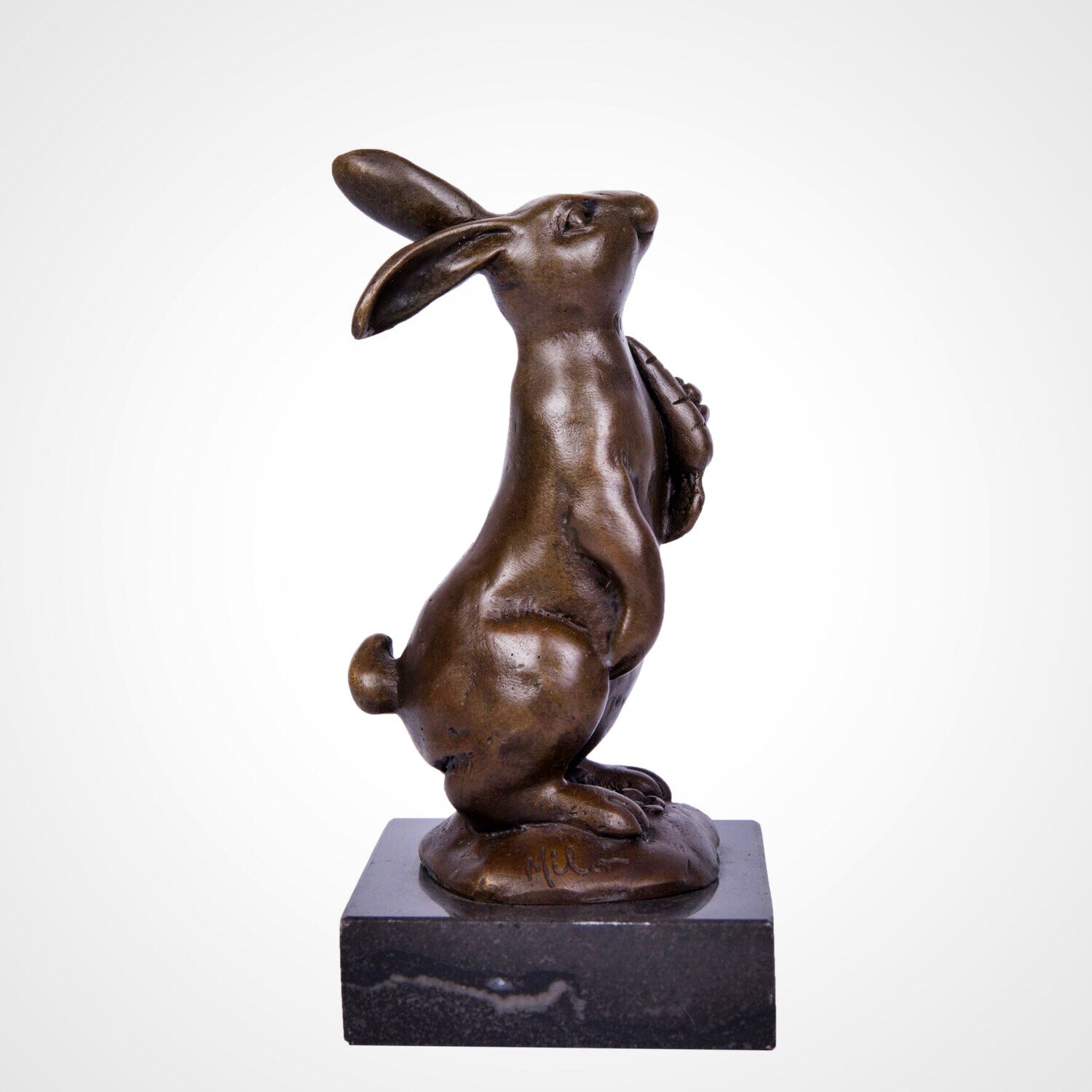 This is a bronze rabbit sculpture: squatting with a carrot in its paws, upright long ears and lively expression, on a black stone base. It’s a cute home decor piece.