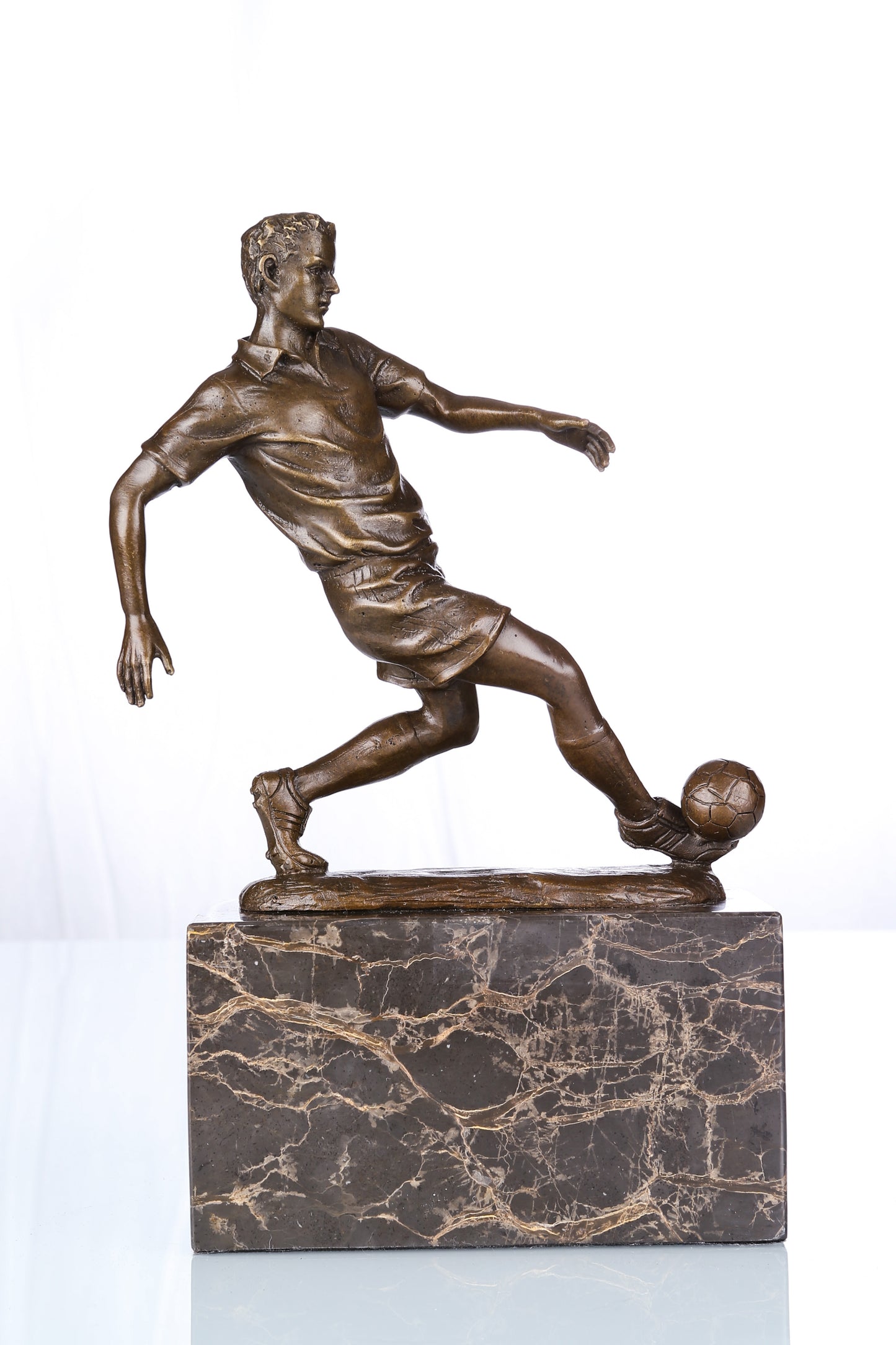 This is a bronze football player sculpture: He stands on the ball with one leg stretched back, arms spread and body leaning forward—muscle and clothing details fit the dynamic movement. The bronze has a dark brown texture, paired with a black-gold veined marble base, exuding competitive vitality and explosive energy.