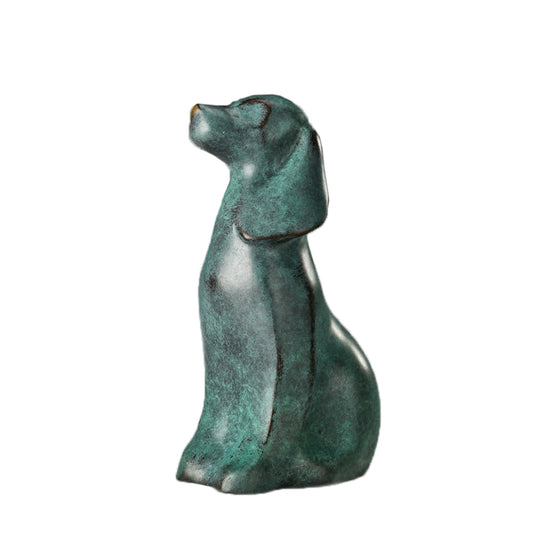 This is a bronze dog sculpture in an abstract style. The dog is in a sitting posture, with a simple and smooth shape. Its surface has a patina texture, and it has a quiet and artistic demeanor. The overall craftsmanship is exquisite. Through simple lines and a unique patina effect, it shows a different artistic charm and has high decorative and ornamental value.